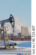 Oil pump jack extracting crude oil on a snow covered oilfield with a refinery in the background. Стоковое видео, видеограф Константин Шишкин / Фотобанк Лори