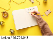 Женщина составляет список дел с рождественским декором на жёлтом фоне. Стоковое фото, фотограф Pixel_shot / Фотобанк Лори