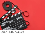 Кинохлопушка с кинолентой на красном фоне. Стоковое фото, фотограф Pixel_shot / Фотобанк Лори