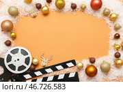 Композиция с кинохлопушкой, кинолентой и рождественскими украшениями на оранжевом фоне. Вид сверху. Стоковое фото, фотограф Pixel_shot / Фотобанк Лори