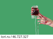 Зомби руки с пакетом крови на зеленом фоне. Празднование Хэллоуина. Стоковое фото, фотограф Pixel_shot / Фотобанк Лори