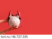 Дьявольские руки с копилкой на красном фоне. Празднование Хэллоуина. Стоковое фото, фотограф Pixel_shot / Фотобанк Лори