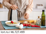 Женщина натирает чеснок на терке за столом на кухне, крупным планом. Стоковое фото, фотограф Pixel_shot / Фотобанк Лори