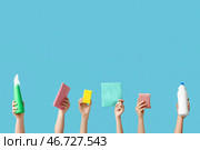 Женские руки держат губки, тряпки и бутылки с моющими средствами на синем фоне. Стоковое фото, фотограф Pixel_shot / Фотобанк Лори