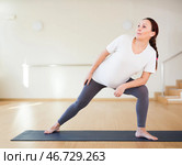 Pregnant woman is engaged in yoga. Extended Side Angle or Utthita Parsvakonasana. Стоковое фото, фотограф Татьяна Яцевич / Фотобанк Лори