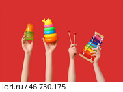 Женские руки с бутылочкой для кормления и игрушками на красном фоне. Стоковое фото, фотограф Pixel_shot / Фотобанк Лори