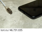 Кабель микро USB и черный смартфон на сером фоне. Персональная электроника. Стоковое фото, фотограф Sergei Gorin / Фотобанк Лори