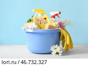Таз с набором чистящих средств и весенних цветов на белом столе на фоне голубой стены. Стоковое фото, фотограф Pixel_shot / Фотобанк Лори