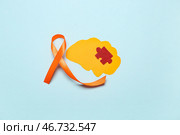 Бумажный мозг с кусочком пазла и оранжевой лентой на синем фоне. Месяц осведомленности о рассеянном склерозе. Стоковое фото, фотограф Pixel_shot / Фотобанк Лори