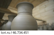 Row of hand made clay pots standing in hot wooden room, ceramics and manufacture concept. Стоковое фото, фотограф David Kashakhi / Фотобанк Лори