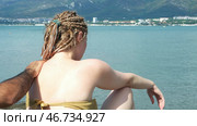 Man hands applying sun protection cream on female with african braids on blue sea beach background, protection from sunburn. Стоковое фото, фотограф David Kashakhi / Фотобанк Лори