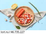Деревянная тарелка с вкусными крабовыми палочками и различными специями на синем фоне. Стоковое фото, фотограф Pixel_shot / Фотобанк Лори
