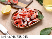 Деревянная тарелка с нарезанными вкусными крабовыми палочками и листьями шпината на бежевом фоне. Стоковое фото, фотограф Pixel_shot / Фотобанк Лори