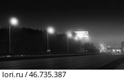 Black and white speed limit camera stands on motorway at entrance to city at night. Стоковое фото, фотограф David Kashakhi / Фотобанк Лори