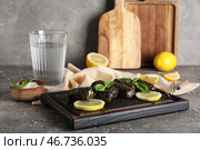 Деревянная доска с вкусными долмами (фаршированные виноградные листья), лимонами, сметаной и стаканом воды на фоне с текстурой. Стоковое фото, фотограф Pixel_shot / Фотобанк Лори