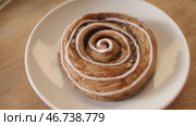 Close-up of sweet puff rolls with honey and white glaze lying on the white plate and rotating on the wooden round board. Стоковое фото, фотограф David Kashakhi / Фотобанк Лори