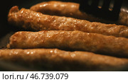 Close-up of thin long pork sausages in natural casing fried on the pan. Стоковое фото, фотограф David Kashakhi / Фотобанк Лори