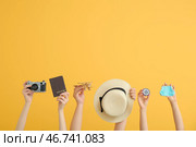 Женские руки с паспортом, фотокамерой, шляпой, деревянным самолетом и компасом на оранжевом фоне. Концепция путешествий. Стоковое фото, фотограф Pixel_shot / Фотобанк Лори