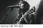 Rock female singer with guitar and microphone performing on stage. Black and white. Стоковое AI-видео, аниматор Елена Никишина / Фотобанк Лори