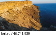 Beautiful view of golden sunset light on rocky cliffs of sea coast with blue waters. Стоковое фото, фотограф David Kashakhi / Фотобанк Лори