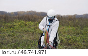 Man in overalls drags parachute to gathering place in field. Стоковое фото, фотограф David Kashakhi / Фотобанк Лори