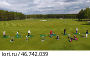 Golfers hitting golf shot with club on course while on summer vacation, aerial. Стоковое фото, фотограф David Kashakhi / Фотобанк Лори