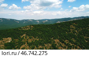 Amazing endless landscape of the high mountain ranges covered by green trees and shrubs against the blue cloudy sky in summer day. Стоковое фото, фотограф David Kashakhi / Фотобанк Лори
