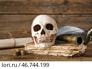 Человеческий череп с древними манускриптами, мечом и подзорной трубой на коричневом деревянном фоне. Стоковое фото, фотограф Pixel_shot / Фотобанк Лори