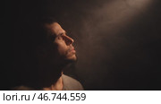 Man gazes upward as divine light pierces surrounding darkness. Стоковое видео, видеограф Илья Шаматура / Фотобанк Лори