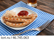 Тарелка с вкусными баварскими колбасками, соусом и квашеной капустой на деревянном фоне. Празднование Октоберфеста. Стоковое фото, фотограф Pixel_shot / Фотобанк Лори