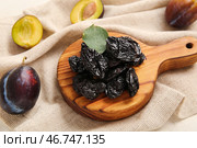 Деревянная доска с вкусными сушеными черносливами на белом фоне. Стоковое фото, фотограф Pixel_shot / Фотобанк Лори