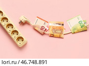 Вилка с евробанкнотами и розетка на розовом фоне. Концепция счетов за электроэнергию. Стоковое фото, фотограф Pixel_shot / Фотобанк Лори