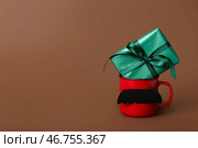 Кубок с бумажными усами и подарок на День отца на цветном фоне. Стоковое фото, фотограф Pixel_shot / Фотобанк Лори