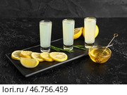 Снимки вкусного лимончелло и миски с медом на черном фоне. Стоковое фото, фотограф Pixel_shot / Фотобанк Лори