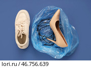 Кроссовки и мусорный мешок с высоким каблуком, обмотанным колючей проволокой на синем фоне. Концепция неудобной обуви. Стоковое фото, фотограф Pixel_shot / Фотобанк Лори