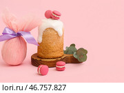 Деревянная доска с пасхальным куличом, сладкими макаронами и подарочным яйцом на розовом фоне. Стоковое фото, фотограф Pixel_shot / Фотобанк Лори