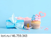 Вкусный кексы с подарочными коробками, пустышкой и декором на голубом фоне. Концепция вечеринки для раскрытия пола. Стоковое фото, фотограф Pixel_shot / Фотобанк Лори
