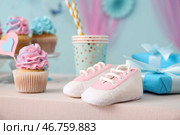 Вкусные капкейки с детскими пинетками и украшениями на столе на фоне голубого цвета. Концепция вечеринки по случаю раскрытия пола ребенка. Стоковое фото, фотограф Pixel_shot / Фотобанк Лори
