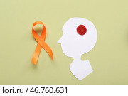 Голова человека из бумаги и оранжевая лента на зеленом фоне. Месяц Осведомленности о Рассеянном Склерозе. Стоковое фото, фотограф Pixel_shot / Фотобанк Лори