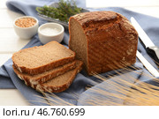 Нарезанный батон хлеба с солью и зернами пшеницы на белом деревянном фоне. Стоковое фото, фотограф Pixel_shot / Фотобанк Лори