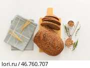 Деревянная доска с нарезанным батоном хлеба, колосьями пшеницы, зернами и тимьяном на белом фоне. Стоковое фото, фотограф Pixel_shot / Фотобанк Лори