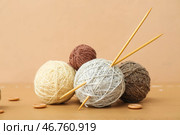 Мотки пряжи, вязальные иглы и пуговицы на коричневом деревянном столе. Стоковое фото, фотограф Pixel_shot / Фотобанк Лори