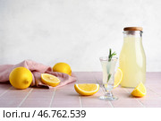 Стопка и бутылка вкусного лимончелло с розмарином на розовом плиточном столе. Стоковое фото, фотограф Pixel_shot / Фотобанк Лори
