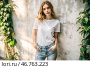 A beautiful young woman in a white T-shirt against the wall. Template layout for hoodie design, print area layout for logo or design. Стоковое AI-изображение, AI-художник Photojuli / Фотобанк Лори