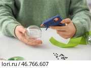 Женщина с клеевым пистолетом украшает рождественскую шар на столе. Стоковое фото, фотограф Pixel_shot / Фотобанк Лори