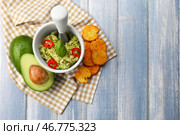 Ступка и пестик с вкусным гуакамоле, спелым авокадо и сухариками на деревянном столе. Стоковое фото, фотограф Pixel_shot / Фотобанк Лори