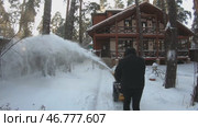 man cleans snow with a snowplow against the background of his snow-covered house. Стоковое видео, видеограф Кутина Татьяна / Фотобанк Лори