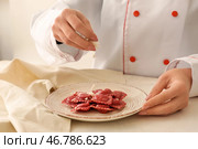 Шеф-повар посыпать вкусные равиоли на тарелку с сыром. Стоковое фото, фотограф Pixel_shot / Фотобанк Лори