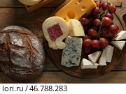 Деревянная доска с ассортиментом вкусных сыров и хлеба на столе. Стоковое фото, фотограф Pixel_shot / Фотобанк Лори
