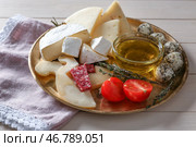 Тарелка с ассортиментом вкусных сыров и масла на деревянном столе. Стоковое фото, фотограф Pixel_shot / Фотобанк Лори